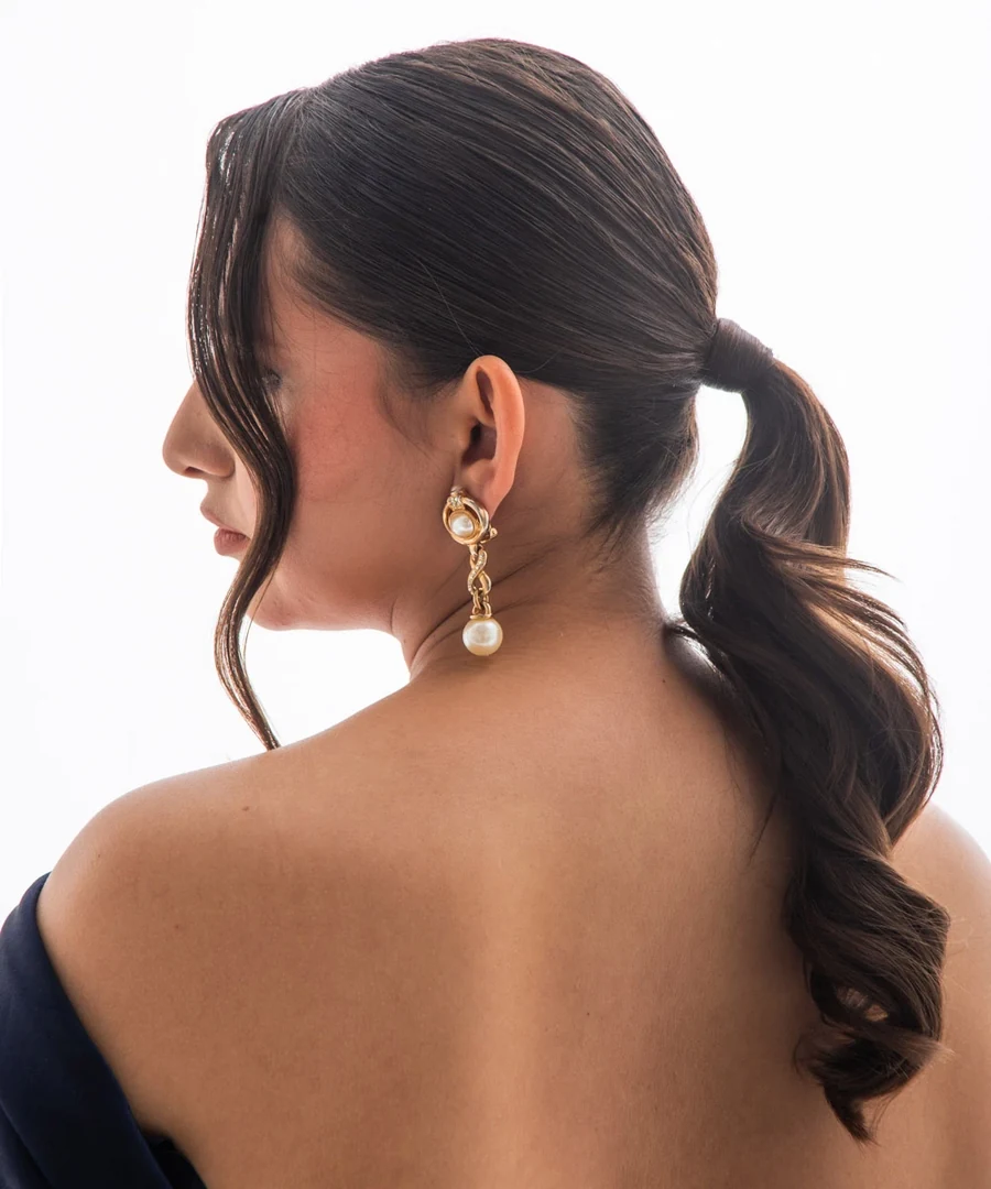 Coleta baja con ondas y mechón suelto junto al rostro.