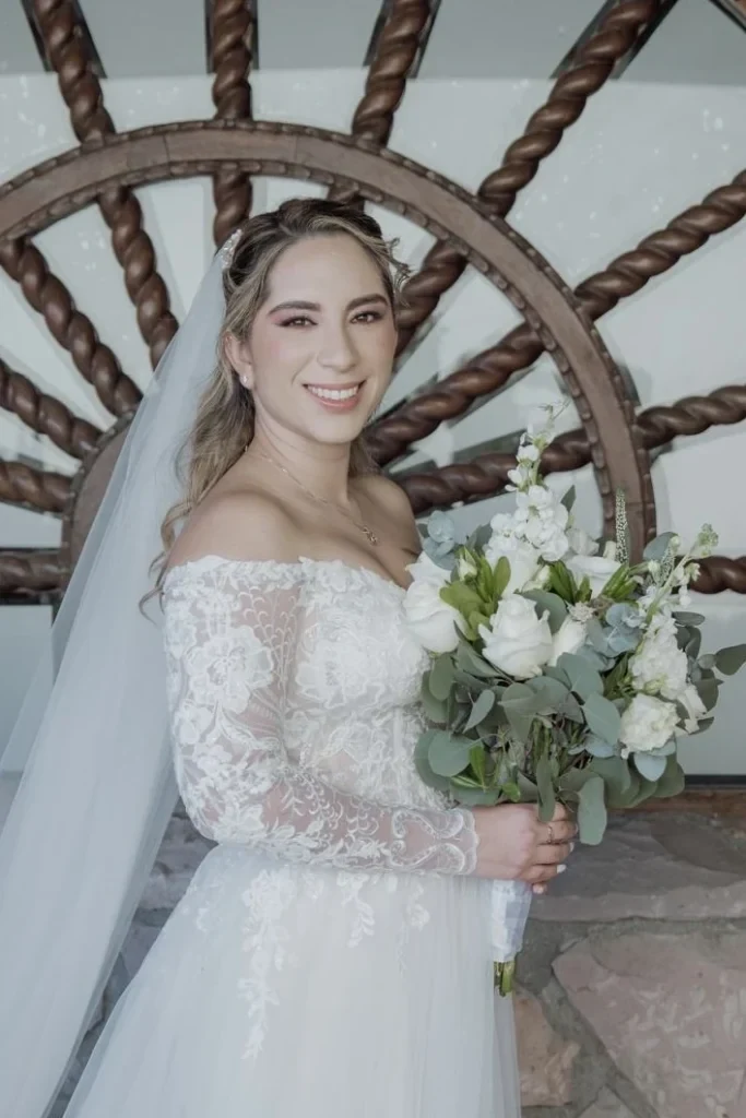 Cabello con ondas, velo y vestido blanco junto a un ramo de flores.