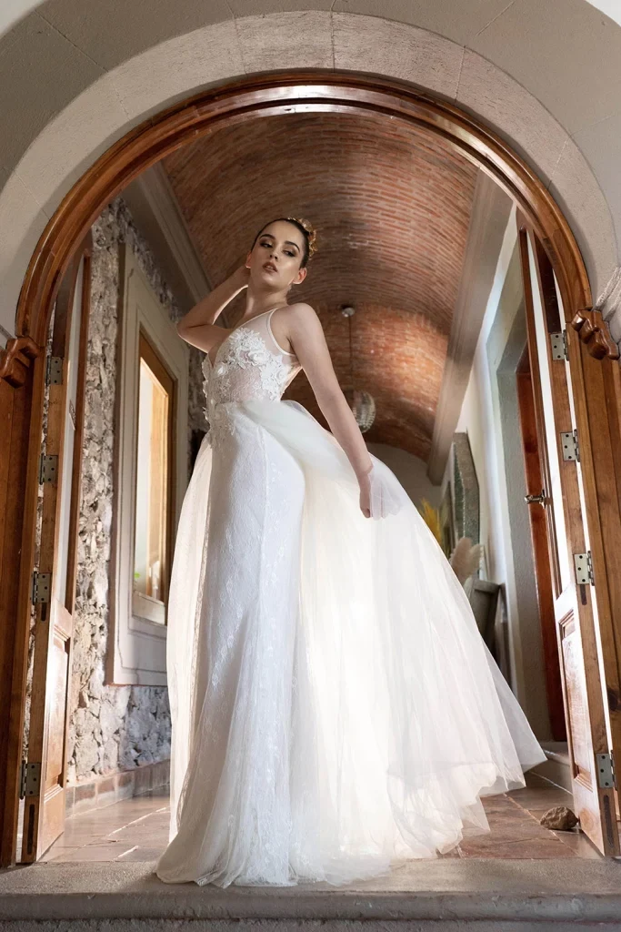 Peinado recogido y vestido blanco en una entrada con arco.
