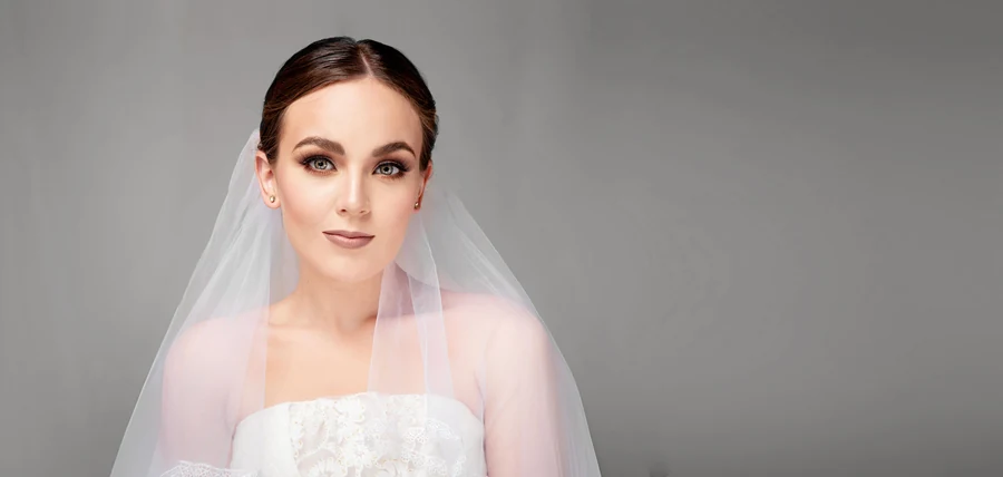 Maquillaje de ojos definido y cabello recogido con velo.