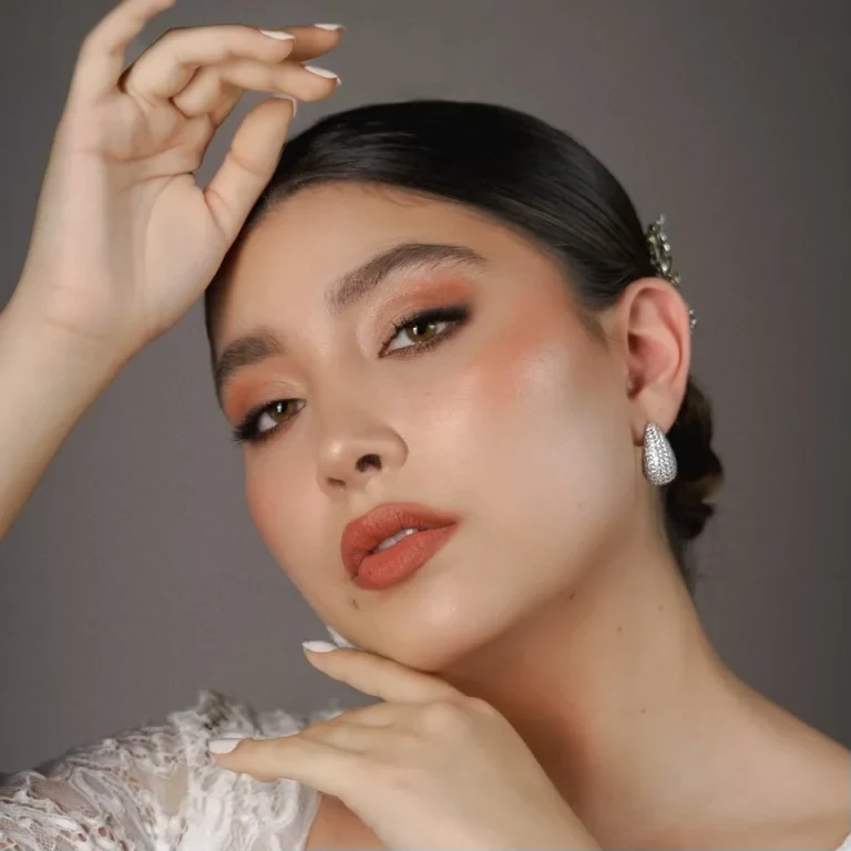 Maquillaje en tonos cálidos con labios terracota y cabello recogido.
