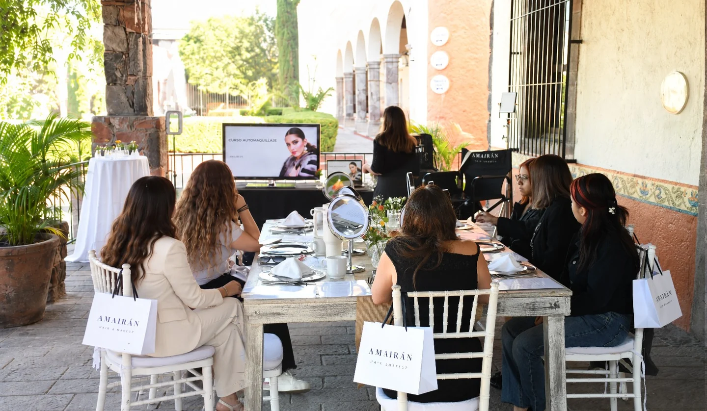 Participantes de un curso de automaquillaje AMAIRÁN alrededor de una mesa con espejos.